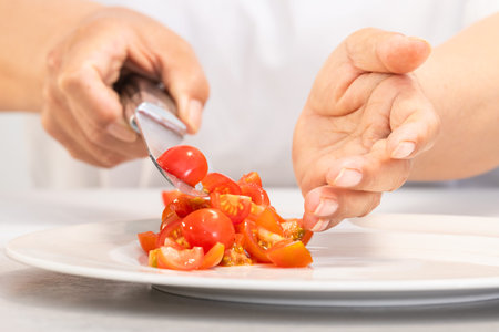 Hands dropping freshly cut tomatoes on a plate