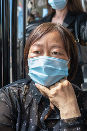 Mature asian woman wearing a mask on a bus: Selective focus. Safety and new public transport rules...