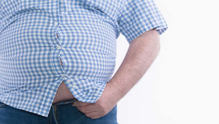 Overweight man trying to fasten too small clothes isolated on white background: Selective focus.の写真素材