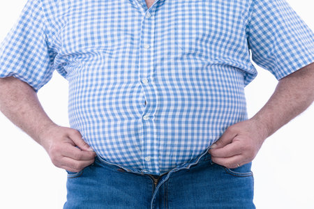 Overweight man trying to fasten too small clothes isolated on white background: Selective focus