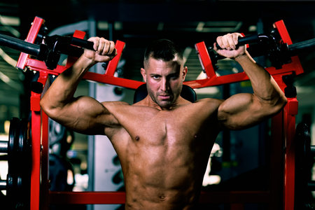 caucasian muscular man on simulator in gym: Selective focus. Bodybuilding and fitness concept