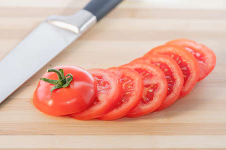 A fresh sliced tomato isolated on a wooden cutting board: Selective focus. Healthy food conceptの写真素材