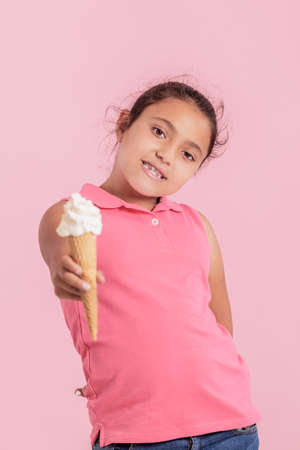 Generous little girl offering an ice cream cone at the cameraの写真素材