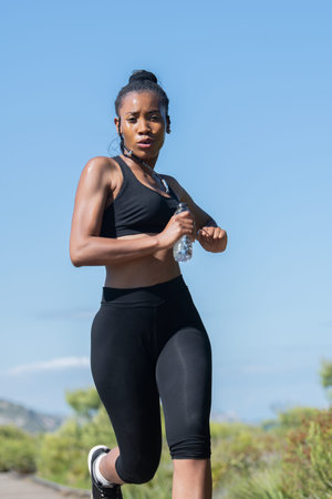 Low shot of afro american woman in sports clothes running: Exercise and strength concept.の写真素材