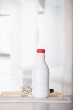 Bottle of milk with a hand whisk on the tableの写真素材