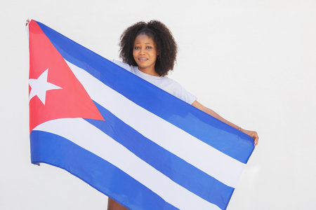 Studio photo of an afro american woman showing a cuban flag in a white backgroundの写真素材