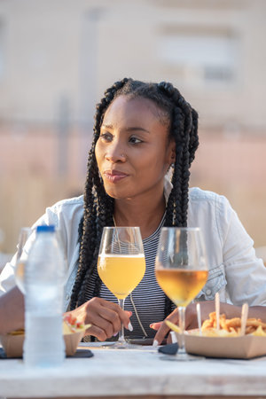 Smiling afro american woman with beer and fast food at an outdoors terrace