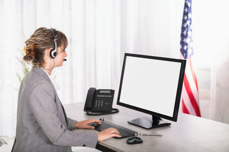 Side view woman customer support call operator in office with blank screen computer