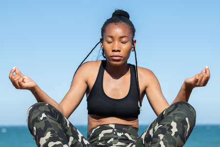 Afro american woman in a meditation pose near the sea: Close up. Meditation conceptの写真素材