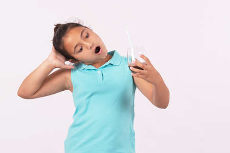 Portrait of a little girl holding a glass of chocolate milk with a straw with expression of astonishmentの写真素材