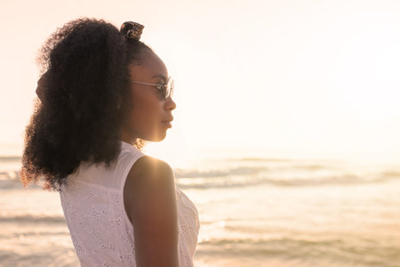 Woman enjoying sunset at the beach with the sea on background.