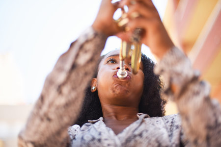 Low angle view of an african woman playing the trumpet in the city outsideの写真素材