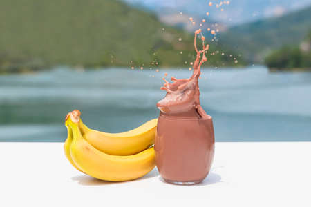 Tempting glass of splashing chocolate shake with bananasの写真素材