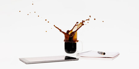 Splashing cup of coffee with phone and notebook