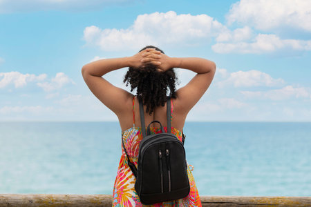 Relaxed woman with a backpack near the seaの写真素材