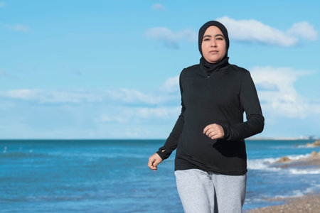 Arabic woman running on the beach near the sea