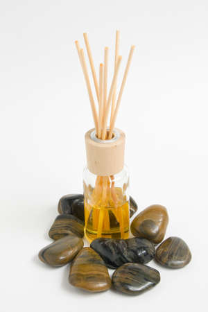 Bottle of air freshener surrounded by stonesの写真素材