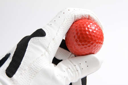 Golf glove holding a red ballの写真素材