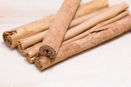 Five brown cinnamon sticks on a wooden boardの写真素材