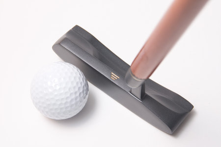 A golf putter hitting a golf ball on white background