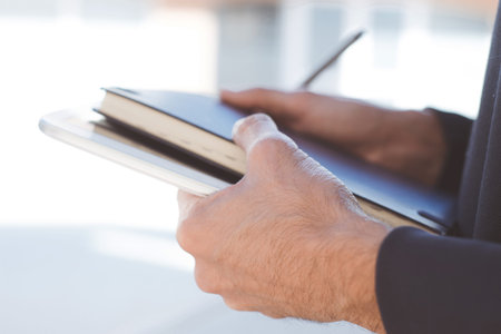 Closeup of young businessman planning with notebook and tablet in his hands