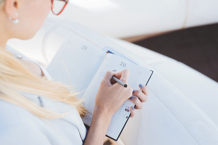 Closeup of young blond businesswoman taking notesの写真素材