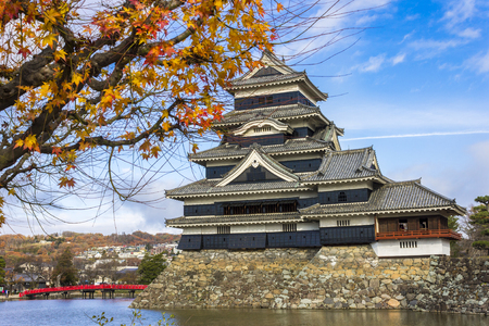 The keep of Matsumoto Castle or Crow Castle in autumn, one of the most famous historic castles of Japan, with a maple tree in the foregroundのeditorial素材