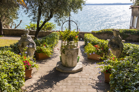 Garden with a well and two statues in Sirmione, northern Italy, with views to Lake Gardaの写真素材