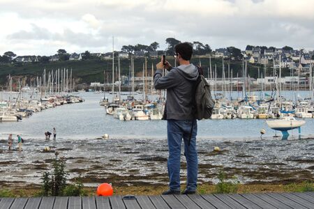 Camaret-sur-Mer, France. Young photographer in fron of the boats and ships of the marinaのeditorial素材
