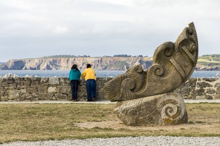 Camaret-sur-Mer, France. Two women looking at the coast from the Sillon with a sculpture in the foregroundのeditorial素材