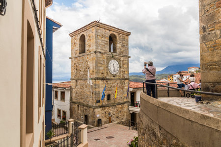 Lastres, Spain. A male photographer looking at the Torre del Reloj (Clock Tower)のeditorial素材