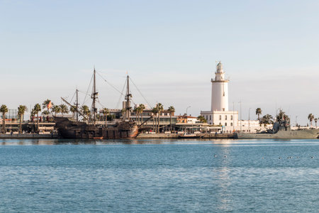 Malaga, Spain. The Galeon Andalucia and the lighthouse at the entrance of the Malaga harbor, called La Farola (The Lantern)のeditorial素材