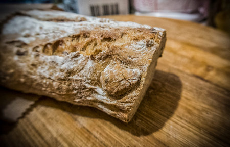 A loaf of bread being cut on a wooden board