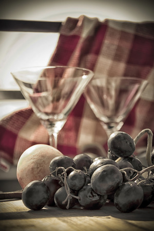 A table set with black grape, two glasses and an orangeの写真素材