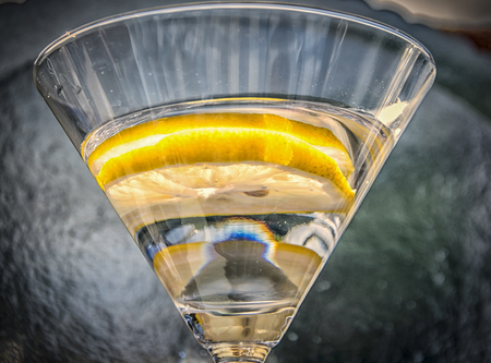 A glass of white cocktail with a slice of lemonの写真素材