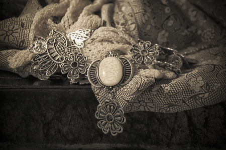 Retro necklace on a vintage fabric in sepia tonesの写真素材