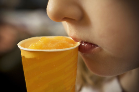 A close-up of a girl eating an orange icecreamの写真素材