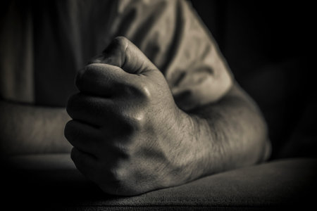 A close-up of a man holding his fist clenched in black and white