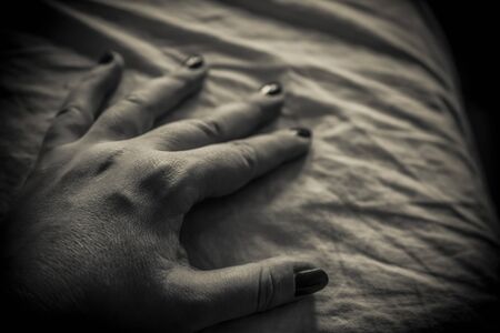 A close-up of a woman's hand on the bed in black and whiteの写真素材