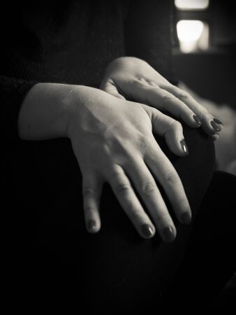 A close-up of a woman with hands on her lap in black and whiteの写真素材