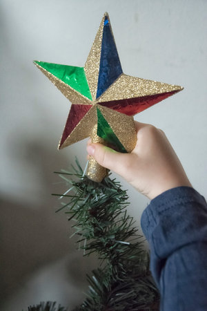 A close-up of girls hands while ornamenting a Christmas tree