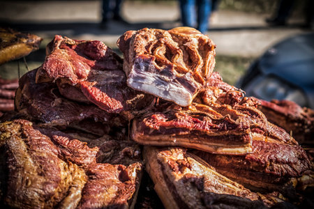 An outdoor stall with pieces of bacon and dried meat being soldの写真素材