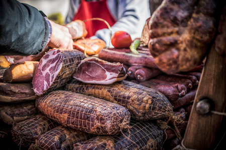 An outdoor stall with pieces of bacon and dried meat being soldの写真素材