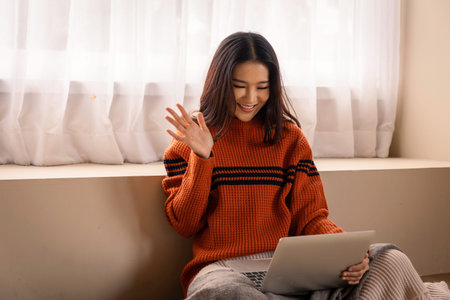 Portrait of a beautiful young Asian woman making facetime video calling with a laptop. she making a...
