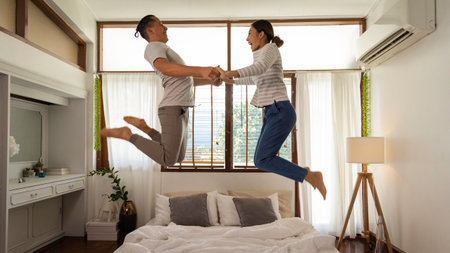 Young Asian couples are enjoying their time together. Have fun and jump into bed in the house. They are a happy family. Husband and wife spend time together in his home.の写真素材