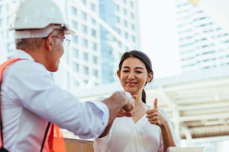 Business men and women shake hands Show the good cooperation in business. By wearing safety helmets...