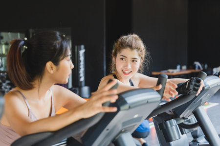 Asian Young woman beautiful people talking and smiling while working out on bike at gym.
