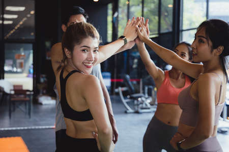 A group of young Asian people who are in good shape at the gym. Picture of cheerful fitness team in gym.They coordinated their hands. Concepts of exercise for health and good shapeの写真素材