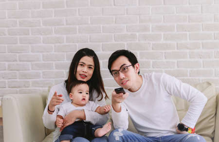 Asian family Consisting of parents and baby watching TV happily. Happy Family Conceptの写真素材