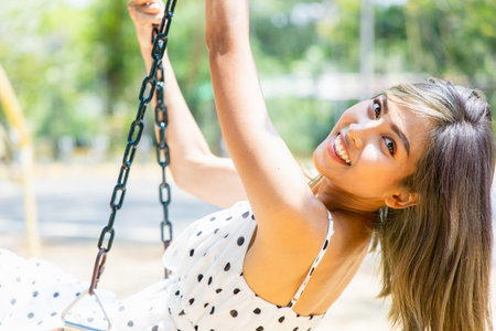 Outdoors portrait stunning young Asian women enjoying on the swing in the park and Natural...